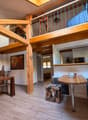 Wooden beams, table, chairs, stools, microwave, open staircase