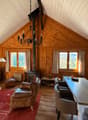 fireplace, wooden walls, chandelier, dining table, chairs, couch, rug, coffee table