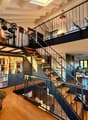 High ceiling, wooden floor, spiral staircase, study with bookshelves, living room with couch, musical instrument, balcony with drum set