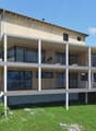 2 story wooden house, concrete balcony, green grassy hill