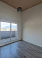 Spacious bedroom with large windows, hardwood-style flooring, and a balcony or terrace overlooking the surrounding area.