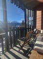 wooden balcony with railings, wooden chairs, lamp, wooden bench, view of mountains