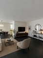 / a large living room with black floors and white furniture and a black table and chairs