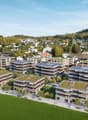 Multiple residential buildings with green roofs, solar panels, landscaped gardens, walking paths, surrounding trees and grass, townscape in the background