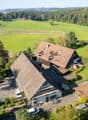 Traditional rural house, nestled in green countryside, multiple outbuildings, car parked in driveway