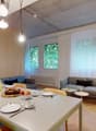 Wooden floor, dining table with cutlery and plates, blue sofa, and couch, lamps