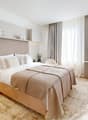 A bedroom with a wooden floor, a large bed with pillows, a desk with a TV, and a white cabinet.