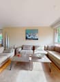 open plan living and dining area, wooden floor, large windows, beige sectional sofa, coffee tables, beige rug, chandelier, framed painting, buffet, dining table and chairs