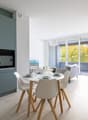 modern kitchen with dining area, white cabinets, white countertops, modern appliances, dining table, chairs, balcony with couch, potted plant