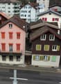 multistory building, brown roof, pink building, windows with shutters, metal railing on balcony