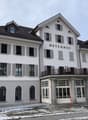 large white building, 'Meyerhof' text on front, large balcony with railing, many windows, white exterior, grey shutters, large arched windows on ground floor