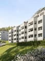 Modern residential complex on slope, balconies, green landscape, mountain view