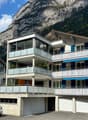 3 story apartment building, white exterior, blue shutters, balconies, garage, mountain view