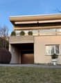 2 story building, raised ground floor, beige exterior, balcony, wooden door, large window, white planter