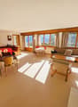 large living room with dining area, wooden furniture, large windows, carpets, picture frame on the wall