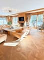 wooden floor, wood paneled walls, fireplace, sofa, armchair, coffee table, TV, glass window