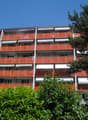multi-story building, multiple balconies with orange railings, white awnings