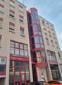 Multi-story building, red trim, large windows, underground garage