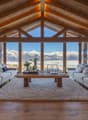 large open living space, wooden beams, large windows, sofa, coffee table, rug, table flower arrangement
