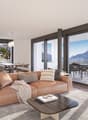 Modern living room, large windows, leather sofa, coffee table, dining table and chairs on balcony, kitchen, carpet