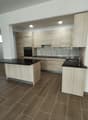modern kitchen with wooden cabinets, black countertops, tiled floor, built-in oven, dishwasher, sink