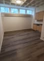 empty room, wooden floor, white walls, kitchen area with cabinets and dishwasher