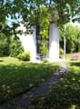 Contemporary house, white walls, glass windows, pathway, garden with green grass, trees, pink lounge chairs