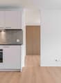 modern kitchen with white cabinets, wooden floor, built-in oven, extractor hood, power outlets, and a window