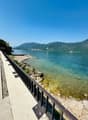 Pathway with railings, rocky shore, clear water, mountains in the distance