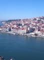 Aerial view of the historic city of Porto, Portugal, situated along the Douro River. The city is characterized by its colorful buildings, winding streets, and iconic bridges spanning the river.
