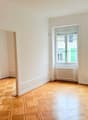 Empty room, white walls, wooden parquet floor, large windows, radiator