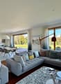 large L-shaped sofa, glass tables, carpet, large windows, glass sliding door, garden view