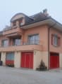 2 story house, red garage doors, balcony, gravel driveway
