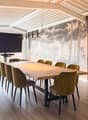 long dining table, 12 chairs, large screen on wall, wooden floor, large windows