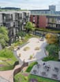 Buildings with balconies, courtyard area with benches and a small park with trees, central open space with people