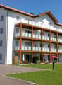 white exterior, balconies, red roof, grassy area, outdoor seating