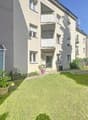 3-story apartment building with balconies, garage, and a well-maintained garden area in the front.