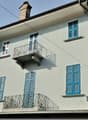 Two story house, blue and white painted walls, chimney, two balconies, windows with blue shutters