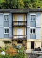 2 story house, yellow and gray exterior, balconies, surrounded by lush greenery
