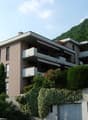 3 story building, balconies, greenery, mountain backdrop