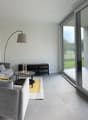 modern style living room, two grey sofas, table, decorative lamp, wall decor, sliding glass doors to balcony with a view