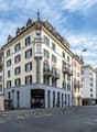 5 story building, beige and white facade, green shutters, balconies, street level shops