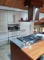 White kitchen cabinets, stainless steel appliances, wooden countertop, gas stove with chimney hood