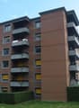 An apartment building with a modern architecture design, many balconies, and yellow windows