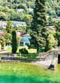 Lakefront villa, multiple buildings, lush greenery, mountain backdrop, swimming pool