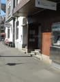 Building exterior with ATM, steps leading to entrance, sign for Zurich Kantonalbank, benches, and a streetlight.