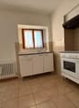 modern minimalist kitchen, white cabinets, tiled floor, gas stove, sink, wooden window frame, white radiator