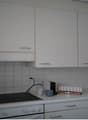 white cabinets, tiled walls, electric stove, coffee maker, coffee cups, small boxes