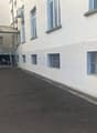 Empty parking lot beside a building, several windows, a garage door, several air conditioning units attached to the wall