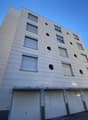 modern apartment building, multiple windows, garage below, bright exterior, four floors